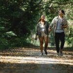 smiling diverse couple holding hands walking in park