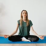 peaceful lady sitting in padmasana pose while meditating on mat